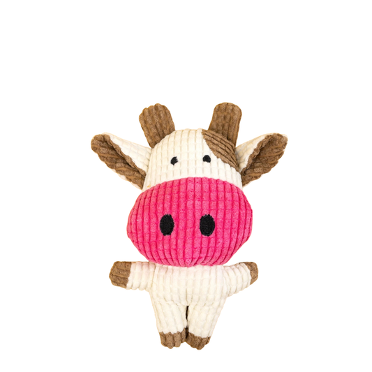 A plush cow-shaped dog toy made of ribbed corduroy fabric, featuring a bright pink nose, cream-colored body and ears, and brown horns and hooves, set against a plain white background.