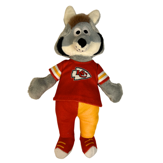 A plush toy dog dressed in a red Kansas City Chiefs jersey and matching red and yellow pants, isolated on a white background.